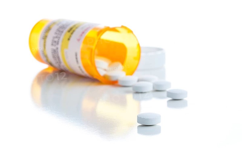 Non-Proprietary medicine prescription bottle and spilled pills isolated on a white background
