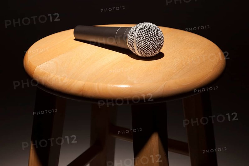 Microphone laying on wooden stool under spotlight abstract