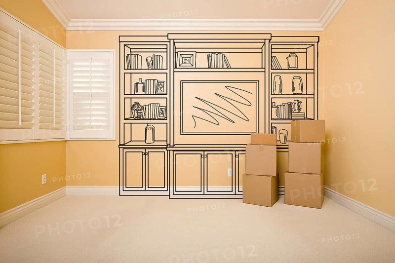 Moving boxes in empty room with shelf design drawing on the wall