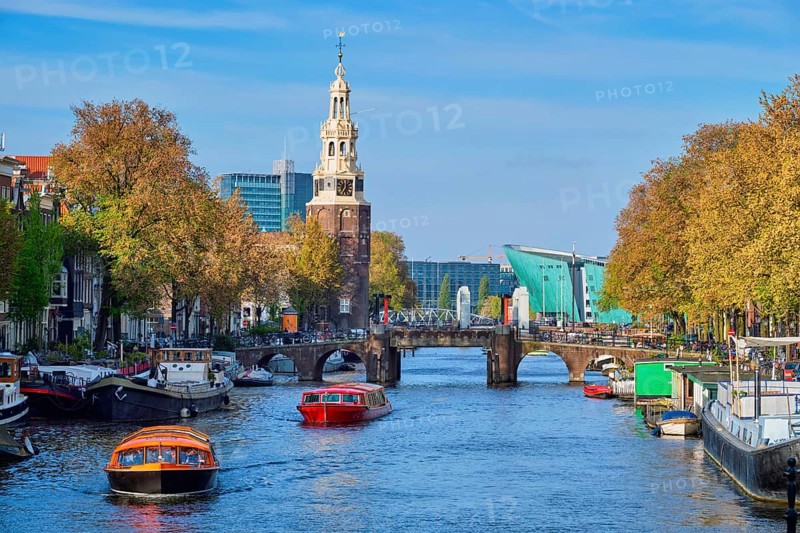 Amterdam cityscape with canal boats and medieval houses and NEMO Science museum and Montelbaanstoren Tower. Amsterdam