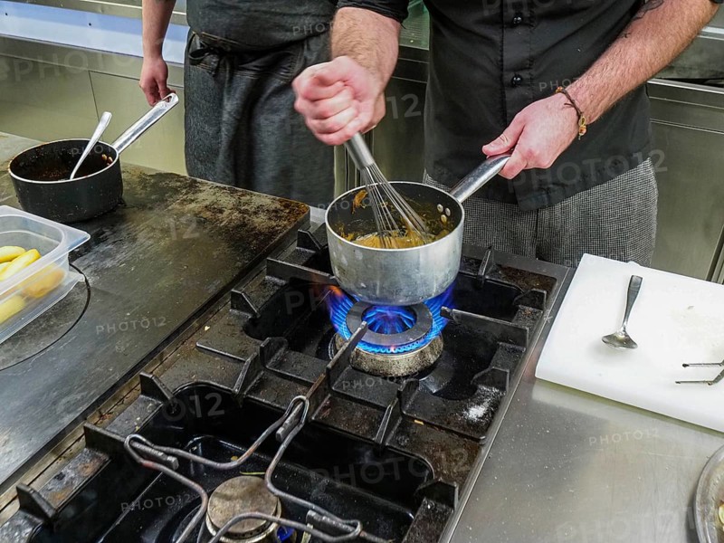 Chef using a hand mixer making a potato sauce cream reduction in a professional kitchen of a restaurant