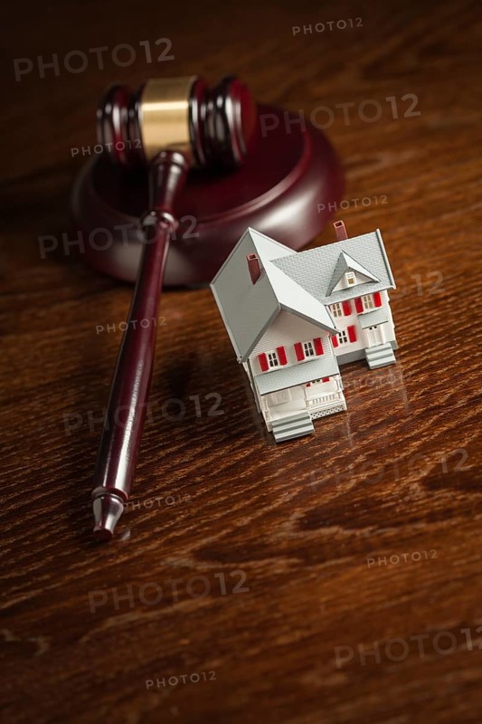 Gavel and small model house on wooden table