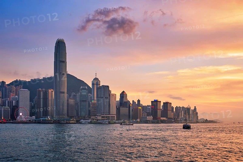 Hong Kong skyline cityscape downtown skyscrapers over Victoria Harbour in the evening with junk tourist ferry boat on sunset with dramatic sky. Hong Kong