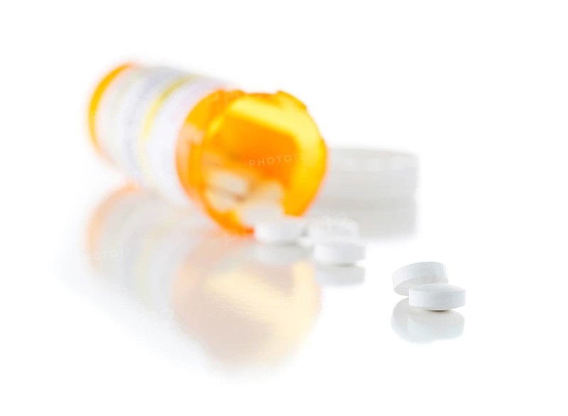 Non-Proprietary medicine prescription bottle and spilled pills isolated on a white background