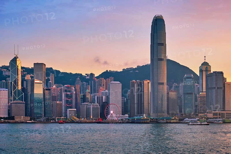 Hong Kong skyline cityscape downtown skyscrapers over Victoria Harbour in the evening with junk tourist ferry boat on sunset with dramatic sky. Hong Kong