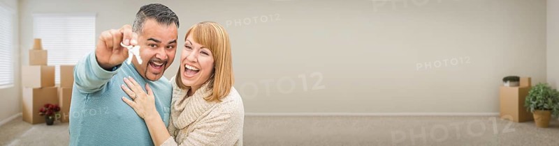 Young adult couple inside room with boxes holding new house keys banner