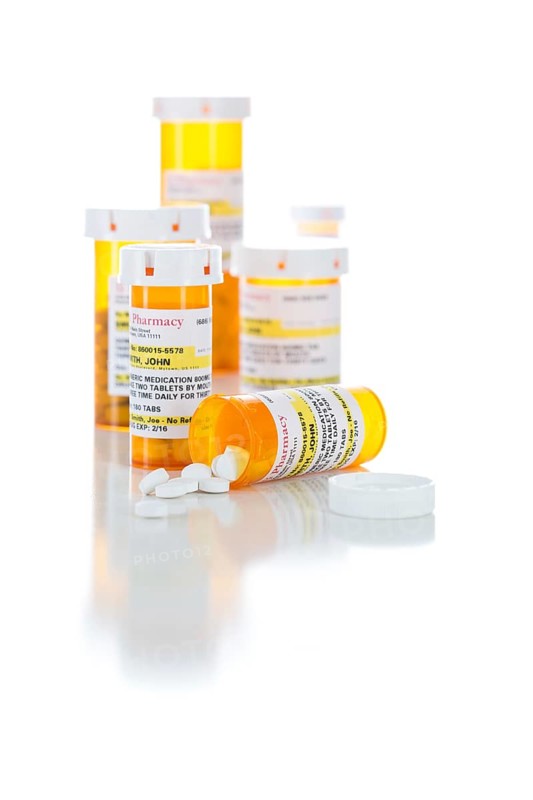 Non-Proprietary medicine prescription bottles and spilled pills isolated on a white background