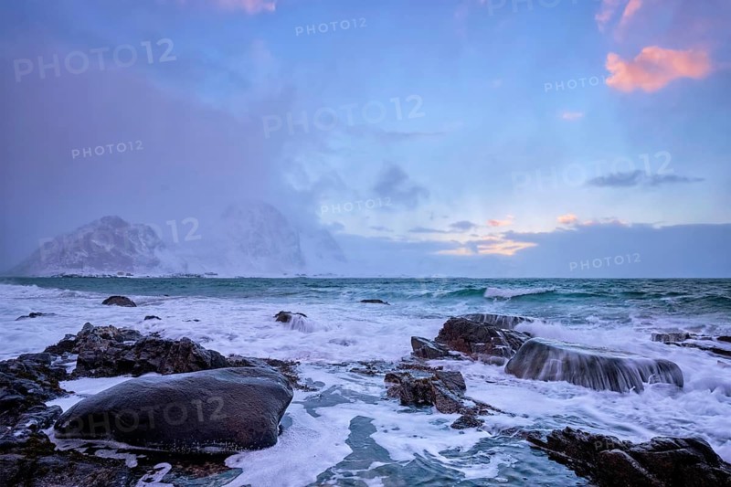 Beach of Norwegian sea on rocky coast in fjord on sunset in winter. Vareid beach