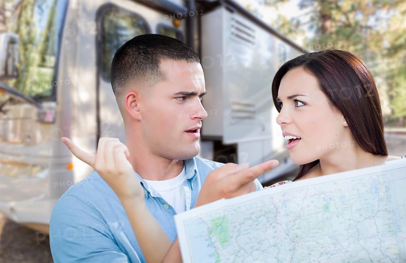 Young lost and confused military couple looking at map in front of RV