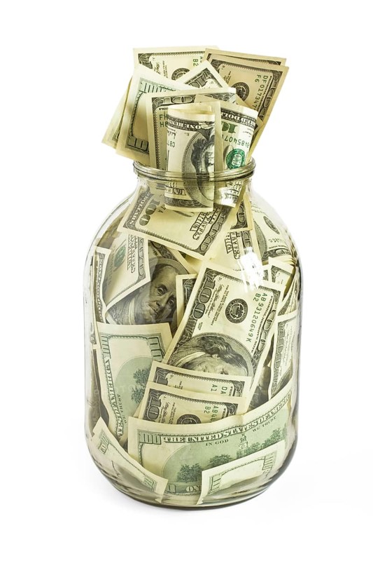 Glass jar full of hundreds of dollars isolated on white background