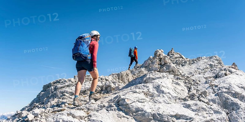 Hiker with climbing helmet on a steep rocky ridge