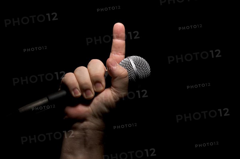 Microphone clinched firmly in male fist with index finger pointing up