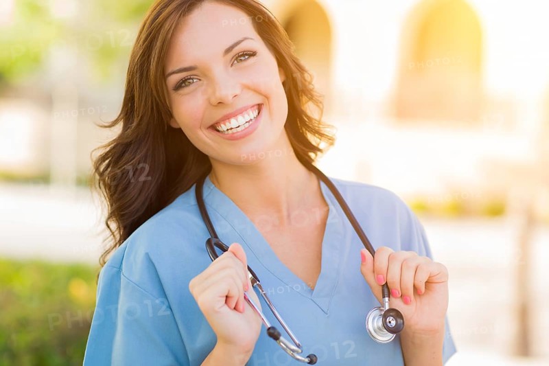 Portrait of young adult female doctor or nurse wearing scrubs and stethoscope outside