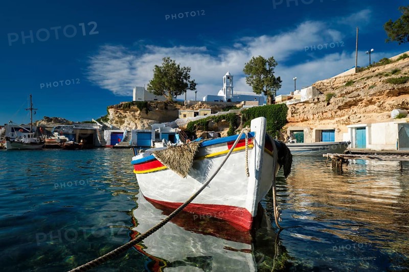 Fishing boats moored in crystal clear turquoise sea water in harbour in Greek fishing village of Mandrakia