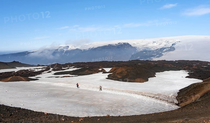 Two hikers on a hiking trail through a snow field