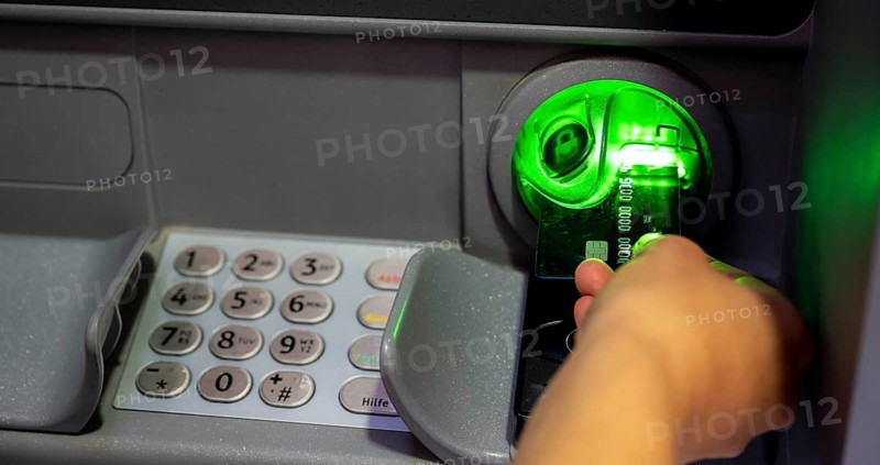 Hand pushes credit card into an ATM