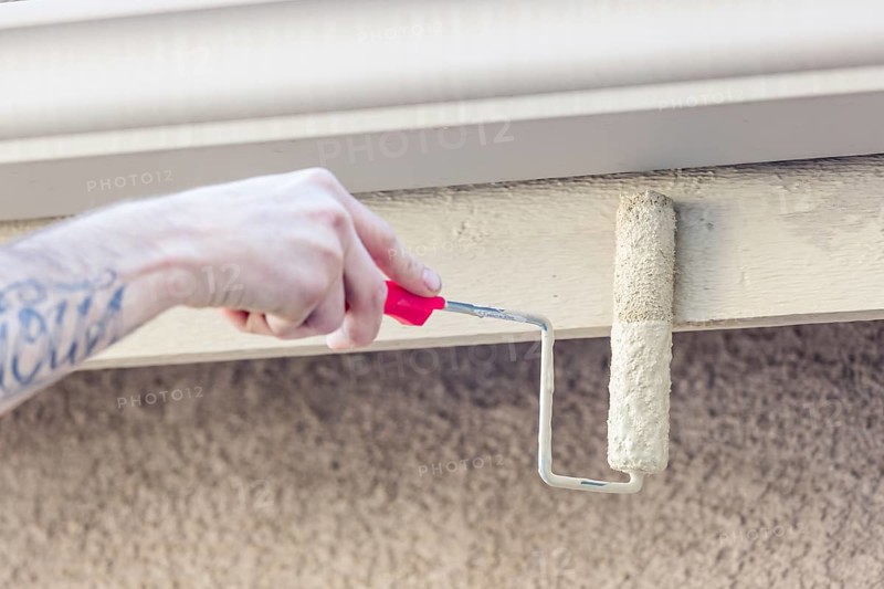 Professional painter using A small roller to paint house fascia