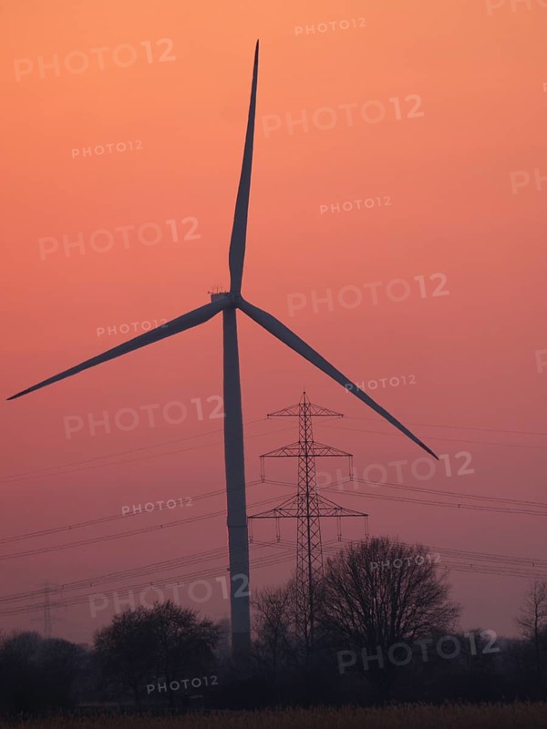 Wind turbine and high-voltage power line against the evening sky in Hamburg's Vier- und Marschlanden