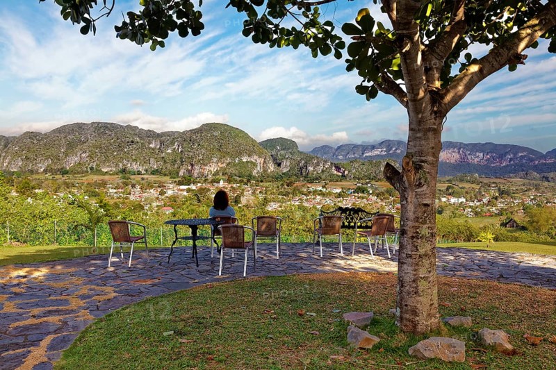 Woman on outdoor seat under tree with view of Valle de Vinales