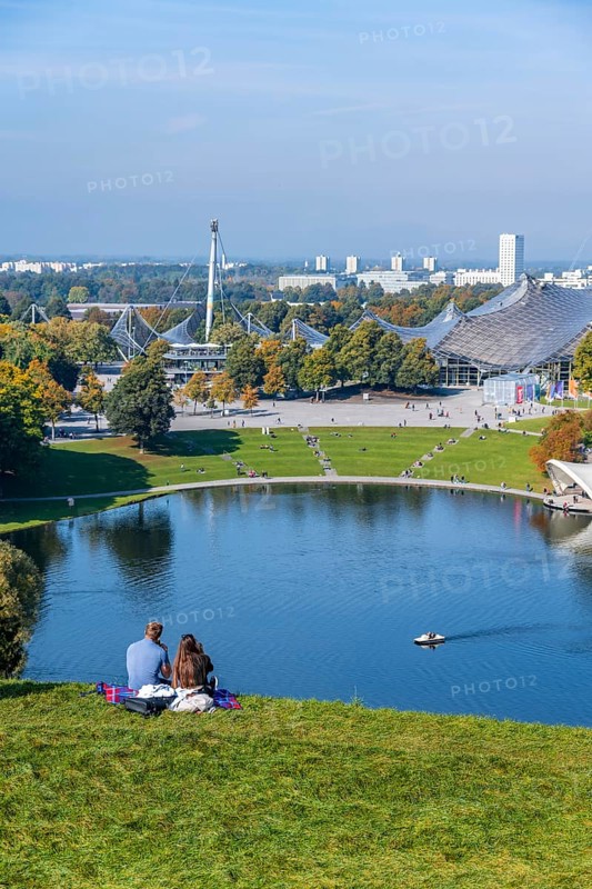 Two people sitting in the park with Olympic lake