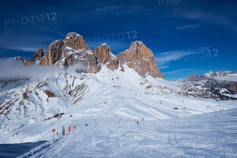 View of a ski resort piste with people skiing in Dolomites in Italy