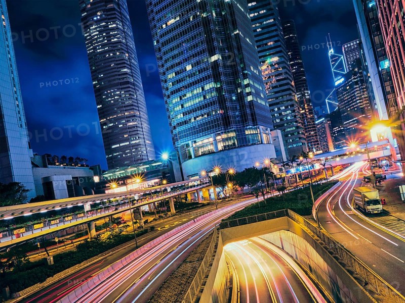 Street traffic in at night. Office skyscraper buildings and busy traffic on highway road with blurred cars light trails. Hong Kong
