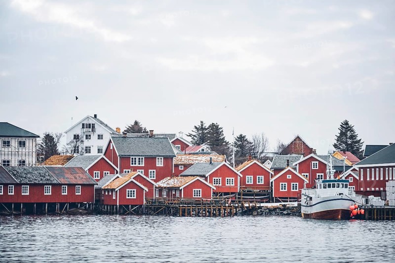Reine fishing village on Lofoten islands with red rorbu houses in winter with snow with fishing boats. Norway