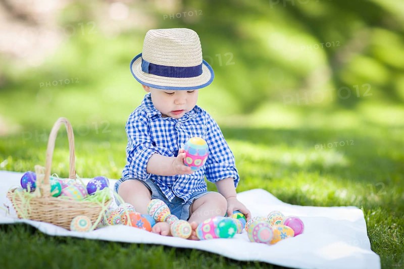 mixed-race chinese and caucasian baby boy outside wearing rabbit ears playing with easter eggs