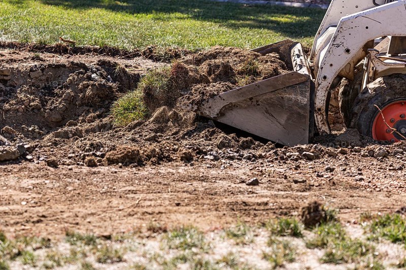 Small bulldozer digging in yard for pool installation