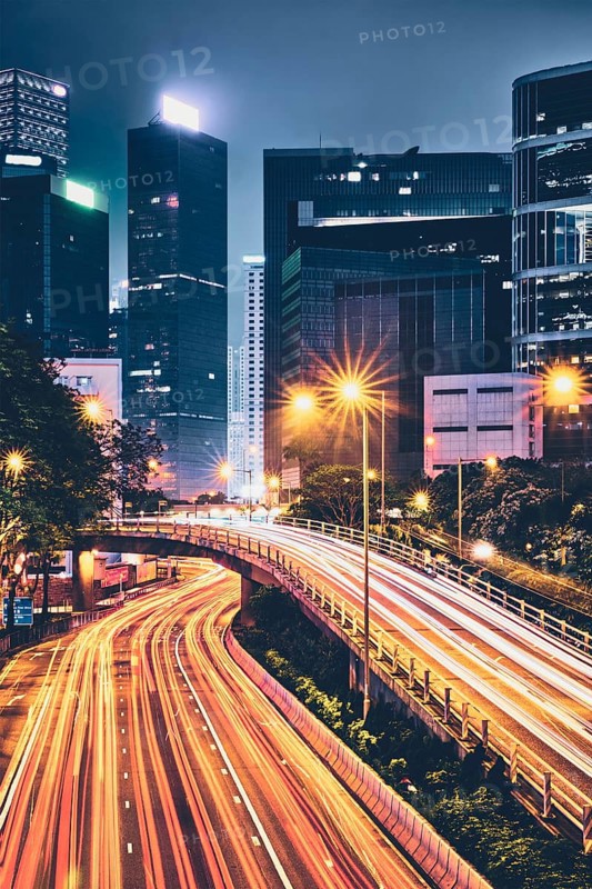 Street traffic in Hong Kong at night. Office skyscraper buildings and busy traffic on highway road with blurred cars light trails. Hong Kong