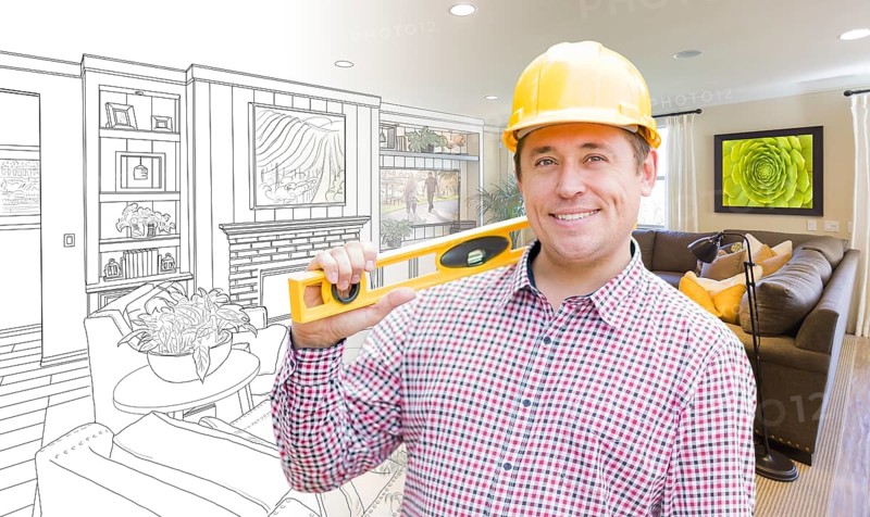 Smiling contractor in hard hat with level over custom living room drawing and photo combination