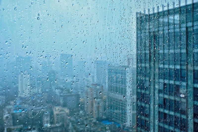 Rain water drops droplets on window glass texture with skyscrapers in background
