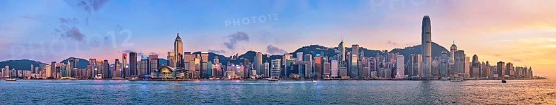 Panorama of Hong Kong skyline cityscape downtown skyscrapers over Victoria Harbour in the evening with junk tourist ferry boat on sunset with dramatic sky. Hong Kong