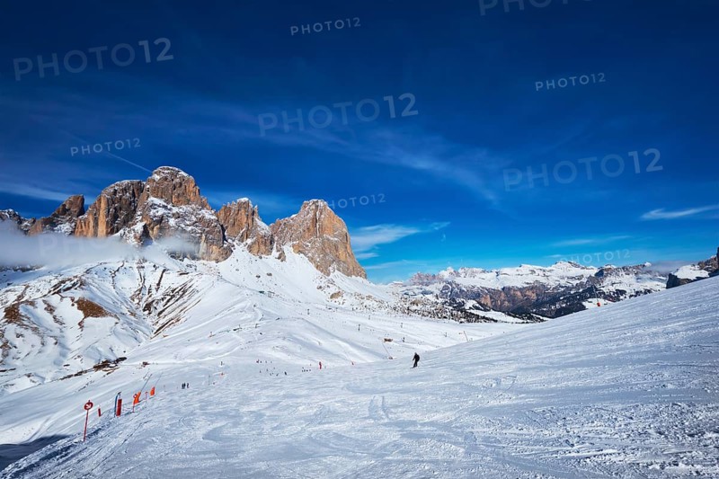 View of a ski resort piste with people skiing in Dolomites in Italy