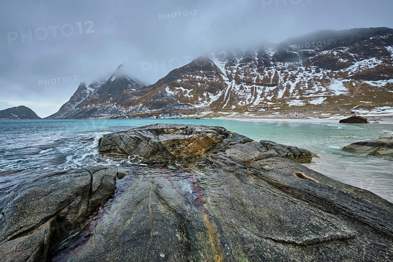 Rocky coast of fjord of Norwegian sea in winter with snow. Haukland beach