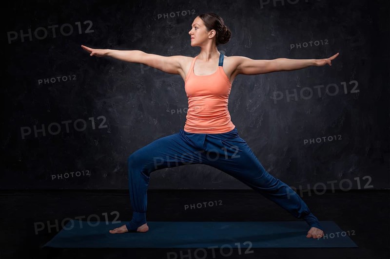 Beautiful sporty fit yogini woman practices yoga asana Virabhadrasana 2