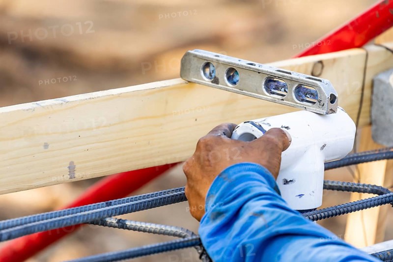 Plumber using level while installing PVC pipe at construction site