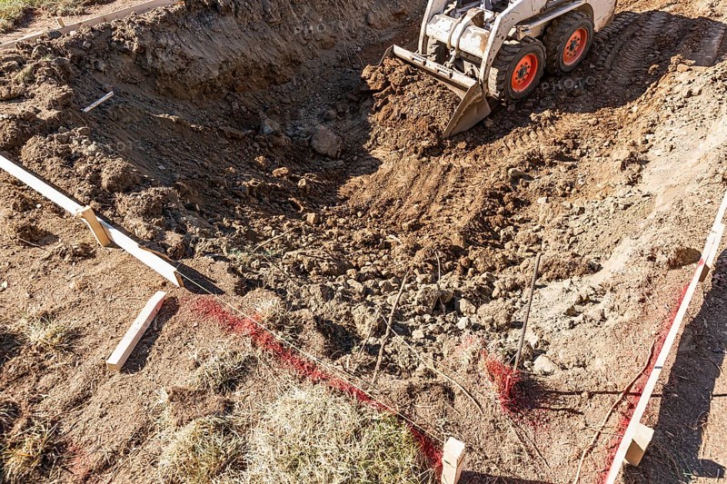 Small bulldozer digging in yard for pool installation