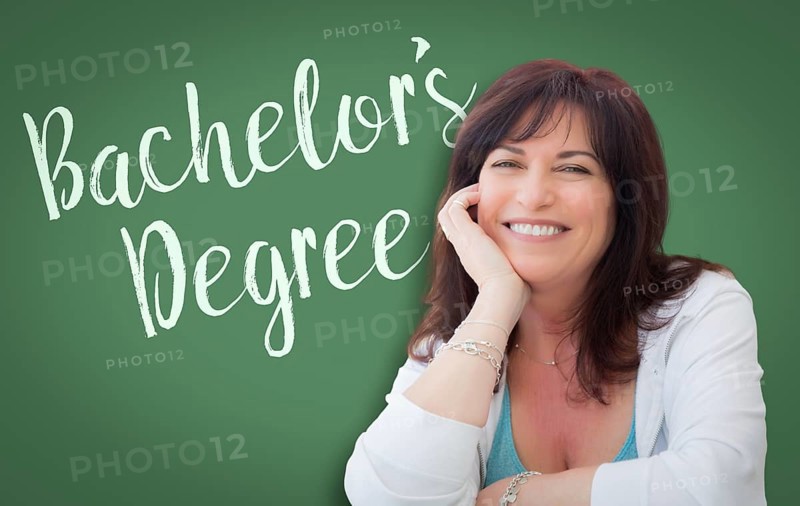 Bachelor's degree written on green chalkboard behind smiling middle aged woman