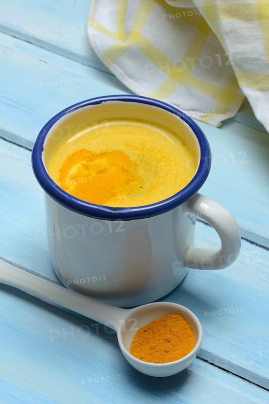 Kurkuma-Milch in Tasse und Kurkumapulver
