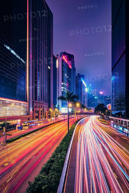 Street traffic in Hong Kong at night. Office skyscraper buildings and busy traffic on highway road with blurred cars light trails. Hong Kong