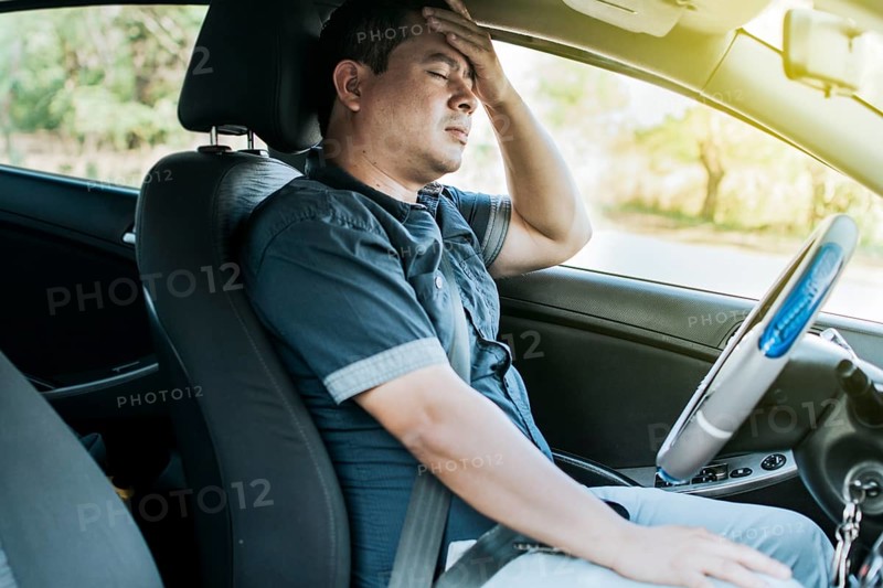 A person in his car with a headache