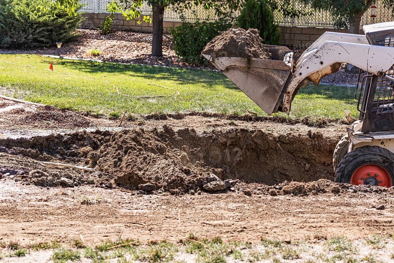 Small bulldozer digging in yard for pool installation