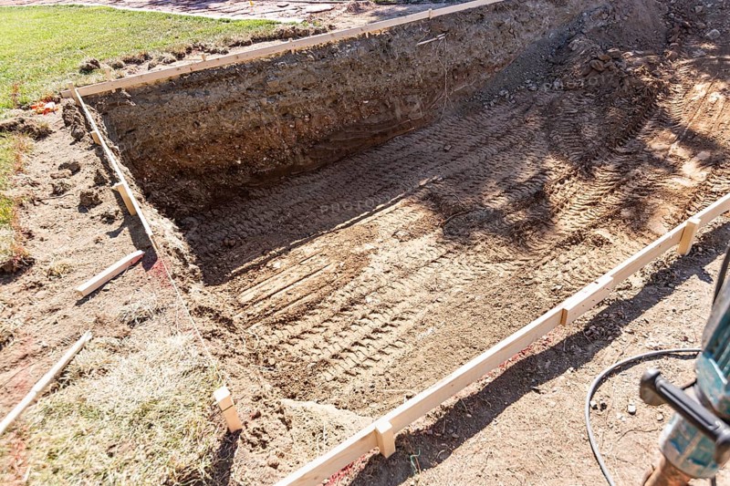 Freshly dug hole in yard preparing for swimming pool installation