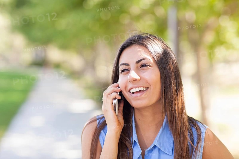 Beautiful young ethnic woman talking on her smartphone outside