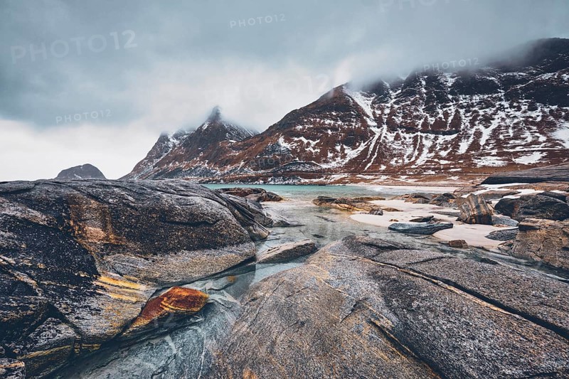 Rocky coast of fjord of Norwegian sea in winter with snow. Haukland beach