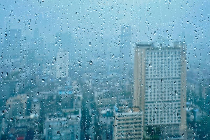 Rain water drops droplets on window glass texture with skyscrapers in background