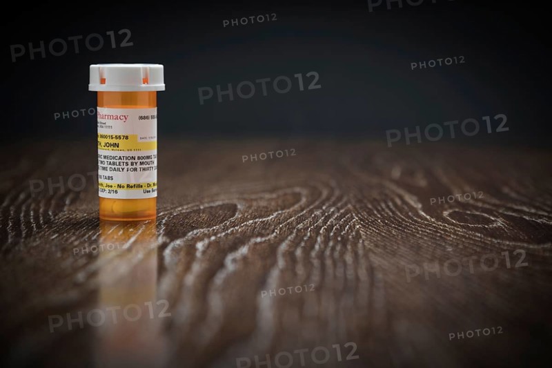 Non-Proprietary prescription medicine bottle on reflective wooden surface