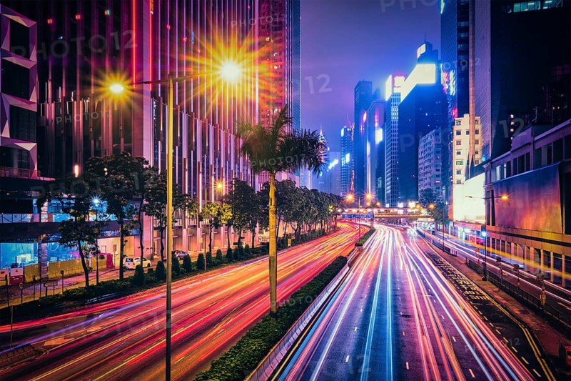 Street traffic in Hong Kong at night. Office skyscraper buildings and busy traffic on highway road with blurred cars light trails. Hong Kong