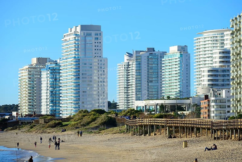 Wooden jetty on the beach in front of high-rise buildings with flats